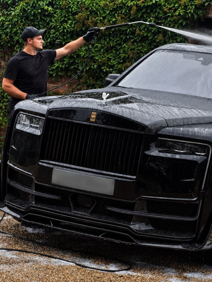 Josh May, founder of Blue Horizon Detailing, pressure rinsing a black Rolls-Royce Cullinan at the owner's home in Warwickshire