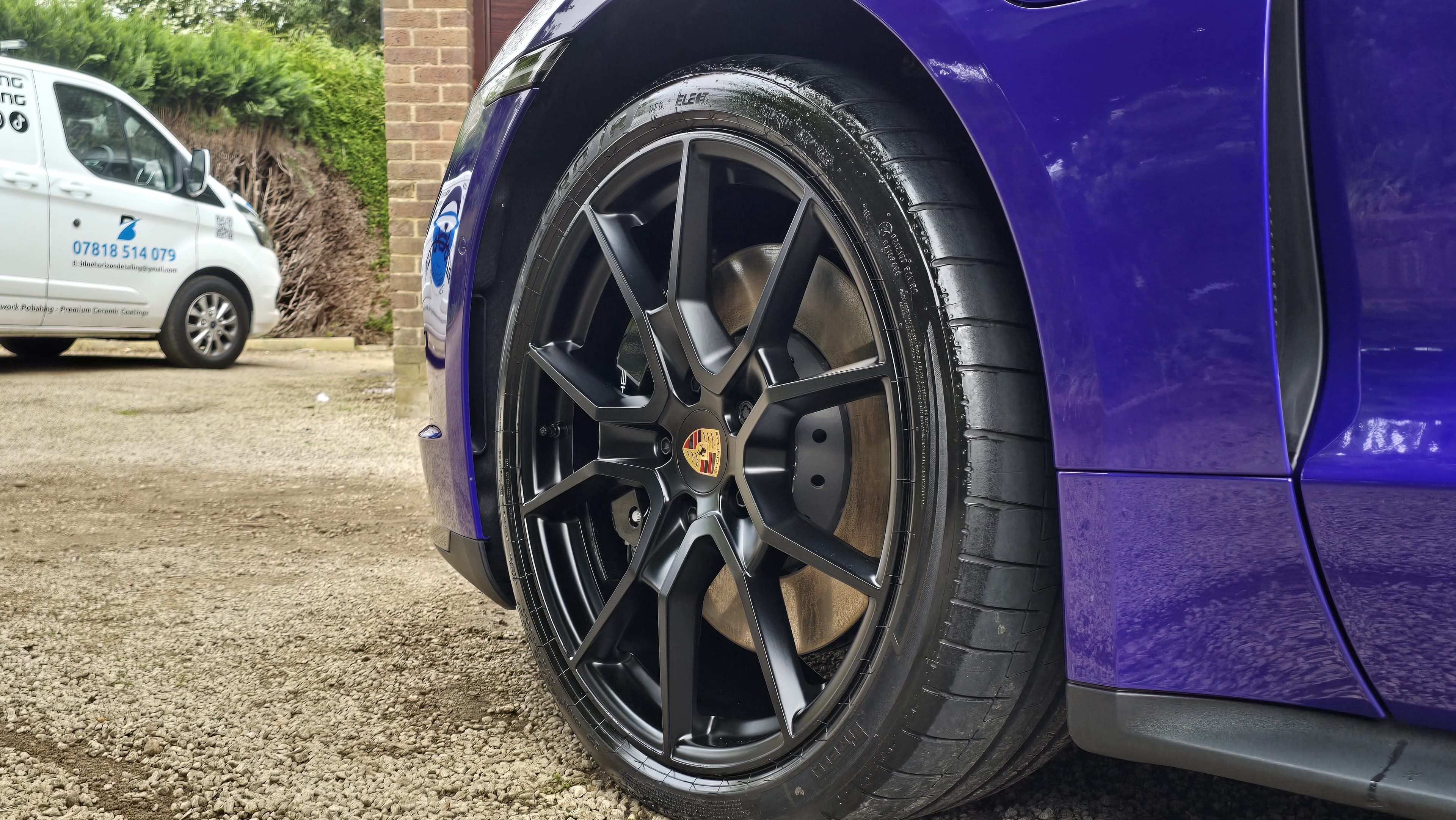 Purple Porsche Taycan alloy wheel close-up with Blue Horizon Detailing branded van visible on-site — mobile valeting Warwickshire